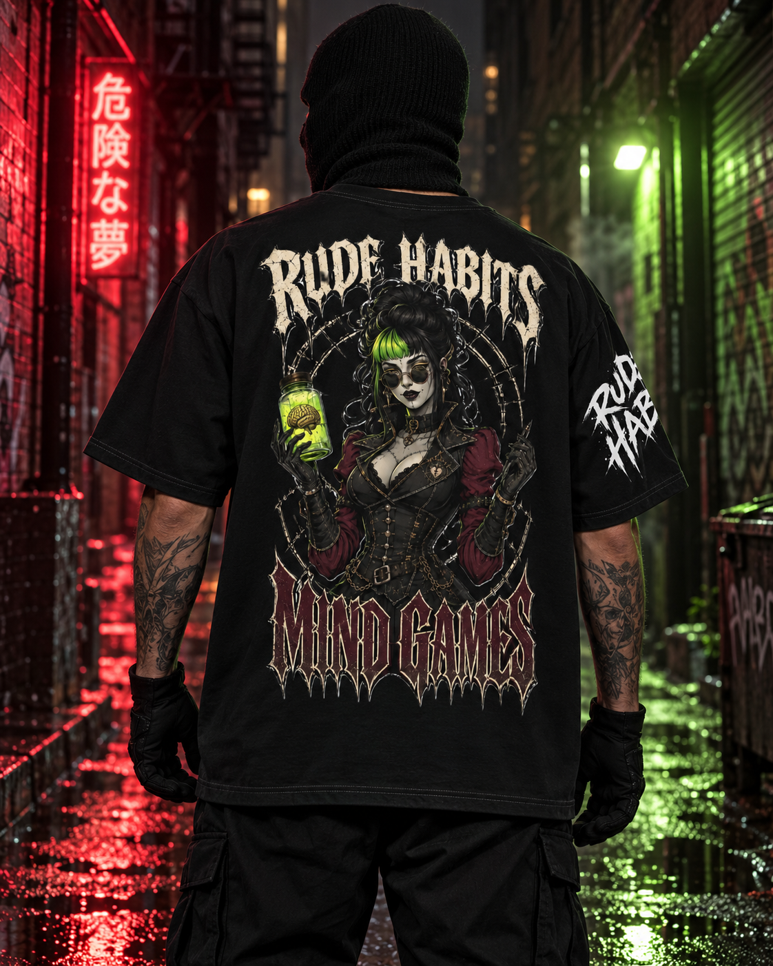 A person standing in a wet urban alley at night wearing a black graphic T-shirt, black pants, and a black balaclava. The shirt back features a large illustrated gothic female figure with green hair and the text 'RUDE HABITS' and 'MIND GAMES'.