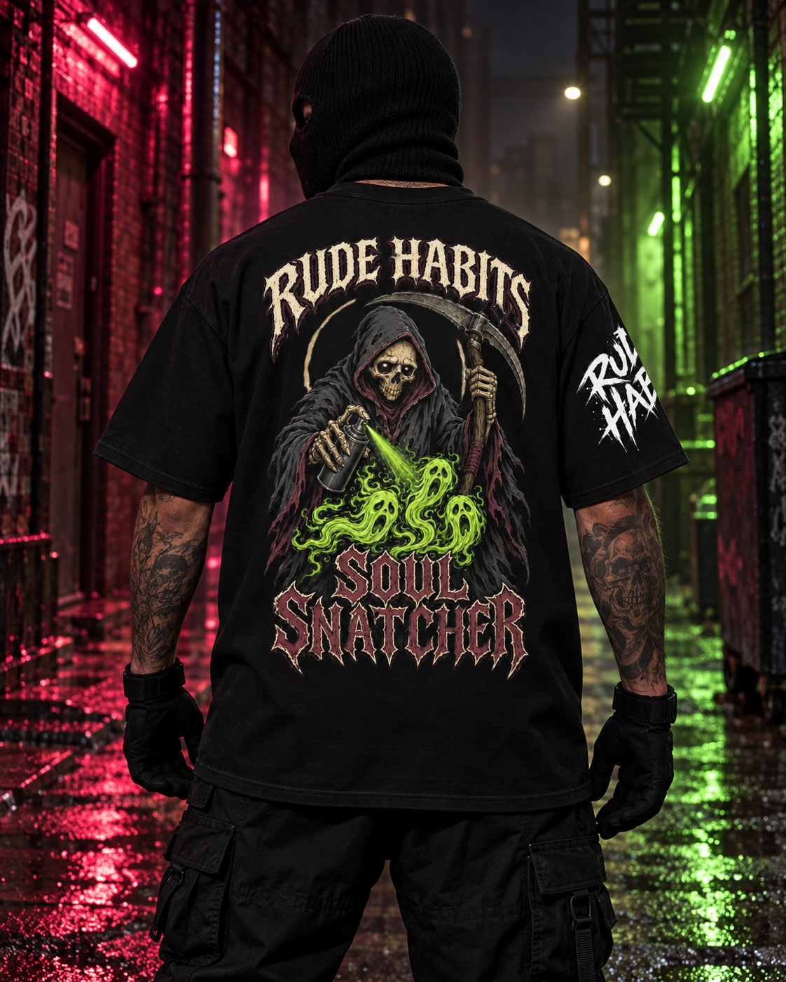 A person standing in a wet urban alley at night wearing a black graphic T-shirt shown from the back. The shirt features a grim reaper illustration with a skull, scythe, green snake-like energy, and the text 'RUDE HABITS SOUL SNATCHER' on the back, plus white text on the right sleeve.