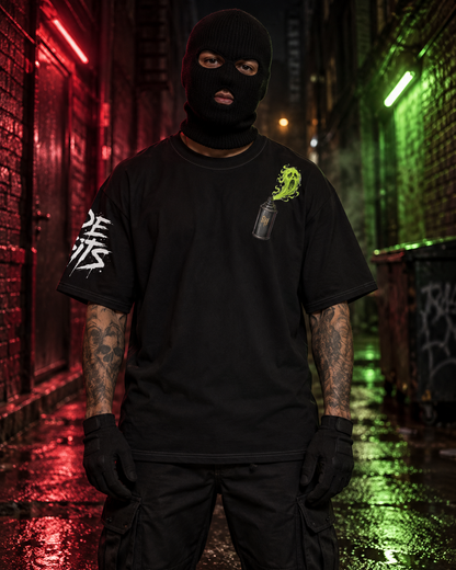 A person wearing a black balaclava, black t-shirt with white graphic on the sleeve and a neon green graphic on the chest, black cargo pants, and black gloves, standing in a wet alleyway at night with red and green lighting.
